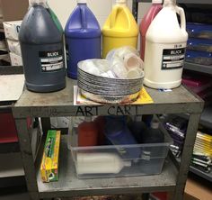 several different types of paint are sitting on a shelf in a room with other items