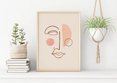 an art print with a face on it next to a potted plant