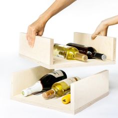 two wooden boxes with wine bottles in them being held by someone's hand over the top