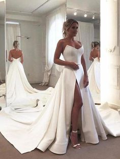 a woman in a white wedding dress standing next to a mirror