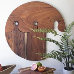 a wooden cutting board sitting on top of a table next to a potted plant