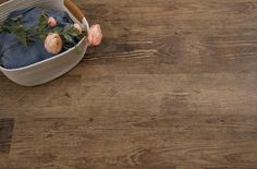 a basket filled with flowers sitting on top of a wooden floor next to a pair of jeans