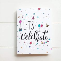 a white card with the words let's celebrate on it and confetti