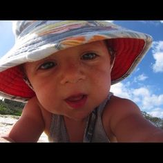 a baby wearing a hat on the beach