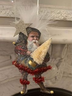 a glass ornament with a santa clause holding a star