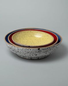 three bowls with different designs on them sitting side by side in front of a gray background