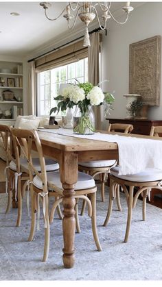 a dining room table with chairs and a vase filled with flowers on top of it