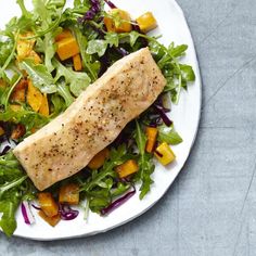 a white plate topped with salad and fish