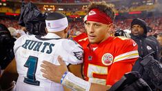 two football players embracing each other in the stands at a game, with fans behind them