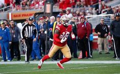 a football player running with the ball in his hand and people watching from the stands