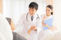 two doctors are talking to each other in the hospital bed while an older woman looks on