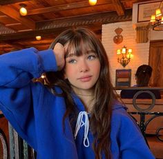 a girl in a blue hoodie is posing for the camera with her hand on her head