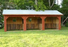 two garages in the middle of a field with grass and trees around them on either side