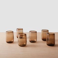 five brown glass cups sitting on top of a wooden table