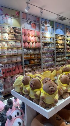 there are many stuffed animals on display in the store, and one is wearing a yellow bib