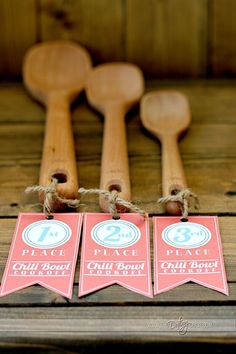 three wooden spoons with tags on them sitting next to each other in front of some wood utensils