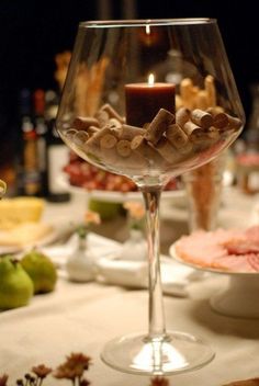 a candle is lit in a wine glass filled with nuts and other food on a table