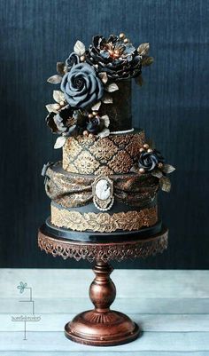 a three tiered cake decorated with flowers and ribbons on a wooden stand in front of a blue wall