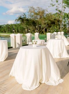 tables with white linens are set up for an outdoor event