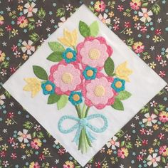 a bouquet of flowers on a black and white floral print fabric with blue ribbon around the edges