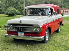 an old red truck is parked in the grass