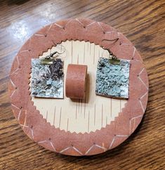 two pieces of wood sitting on top of a wooden table next to a pair of earrings