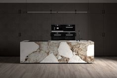 an island in the middle of a kitchen with marble counter tops and appliances on it