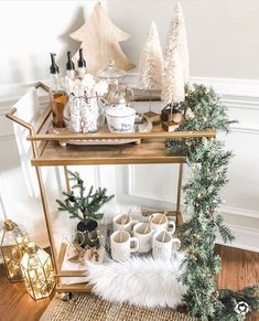 a gold bar cart with christmas decorations and coffee mugs sitting on top of it