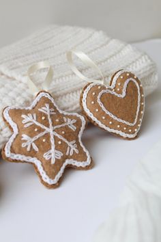 two gingerbread cookies sitting next to a white knitted hat and mitten on a table