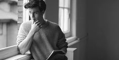 a man sitting on a window sill reading a book