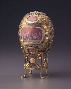 an ornately decorated gold egg with paintings on it