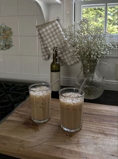 two glasses filled with liquid sitting on top of a wooden counter