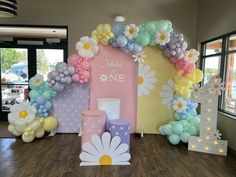 balloons and decorations are arranged in the shape of a flower arch for a baby's first birthday party