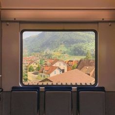 a view from the inside of a train looking out at houses and mountains in the distance