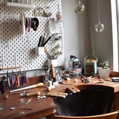 a wooden desk topped with lots of crafting supplies next to a wall mounted clock