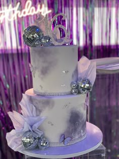 a three tiered white cake with silver decorations