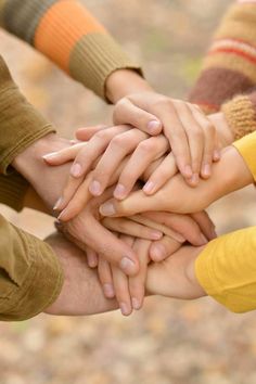 a group of people stacking their hands in the middle of each other's arms