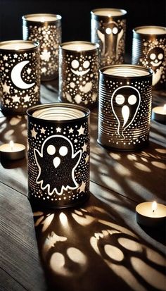 some candles are sitting on a table with black and white designs in them, all lit up