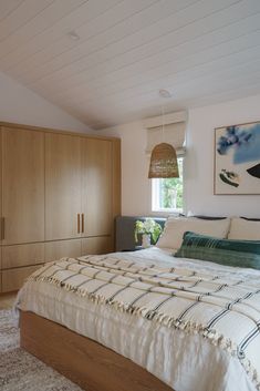 a large bed sitting in a bedroom next to a wooden dresser and lamp above it