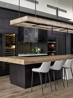 a modern kitchen with black cabinets and marble counter tops, bar stools and an island in the middle