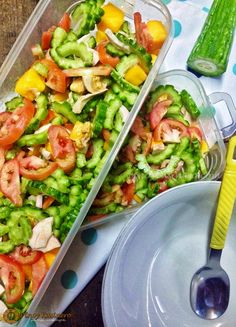 two plastic containers filled with vegetables on top of a table next to a fork and spoon