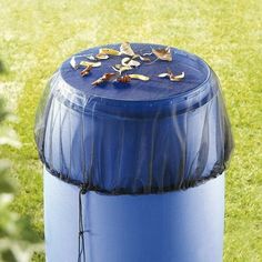 a blue trash can sitting on top of a lush green field