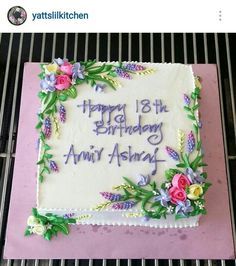 a birthday cake with flowers on it sitting on top of a grilling rack,