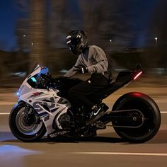 a man riding on the back of a white motorcycle down a street at night time