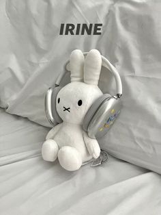 a white stuffed animal with headphones on it's ears sitting on a bed