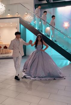 a man and woman dressed in formal wear walking down stairs