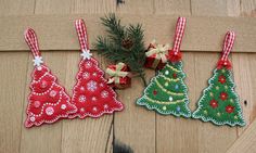 three christmas tree ornaments hanging on a wooden wall next to a pine tree and presents