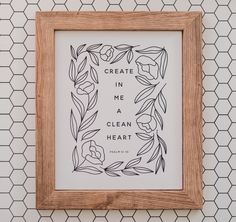 a wooden frame hanging on the wall with an art print saying create in me a clean heart