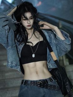 a woman in black top and jean jacket standing next to stairs with her hands on her head