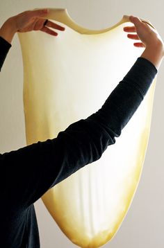 a woman is holding up a large piece of yellow material to the side of her face